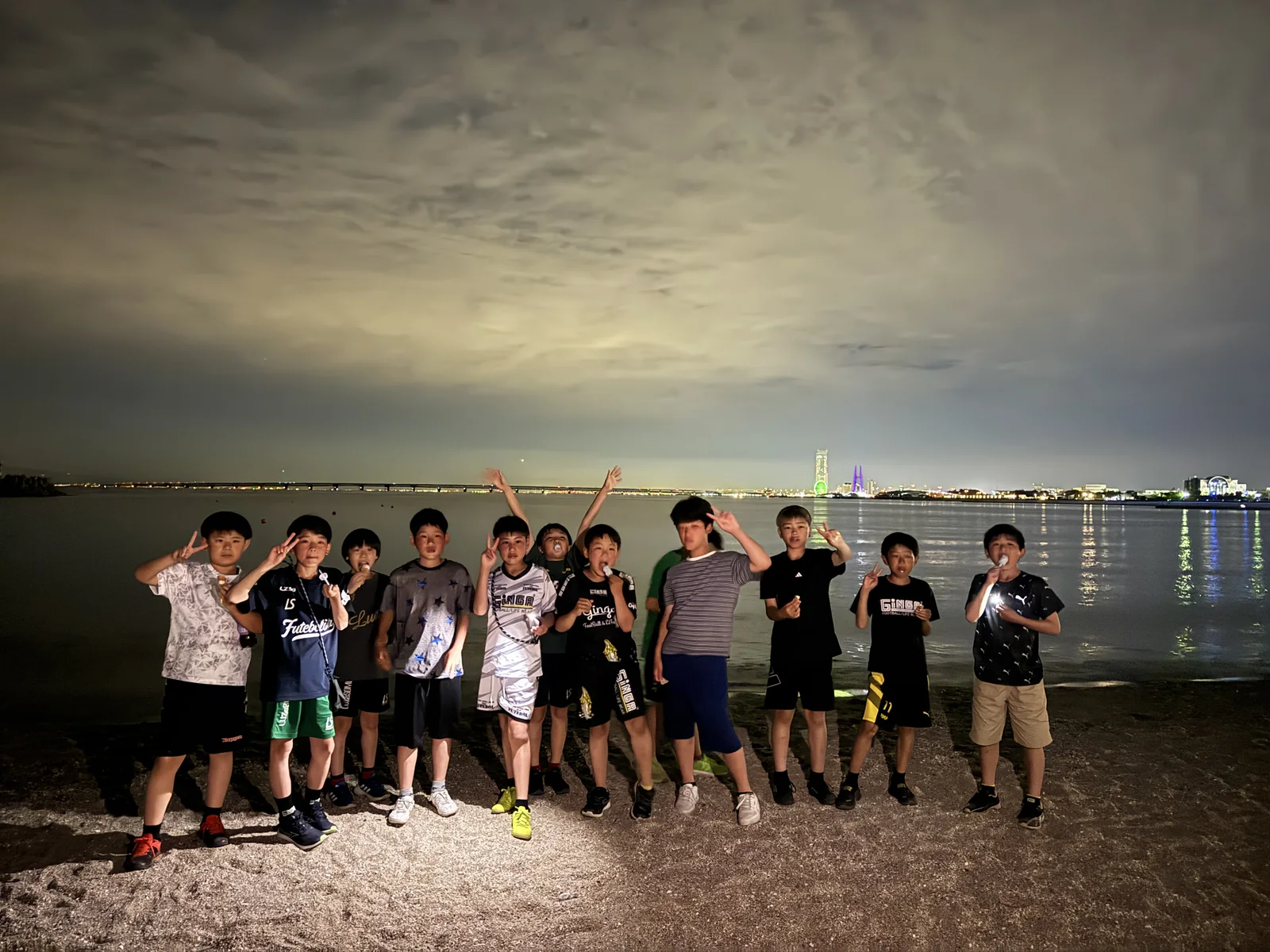 夕方の海辺に並ぶ真栄FCの選手たち
