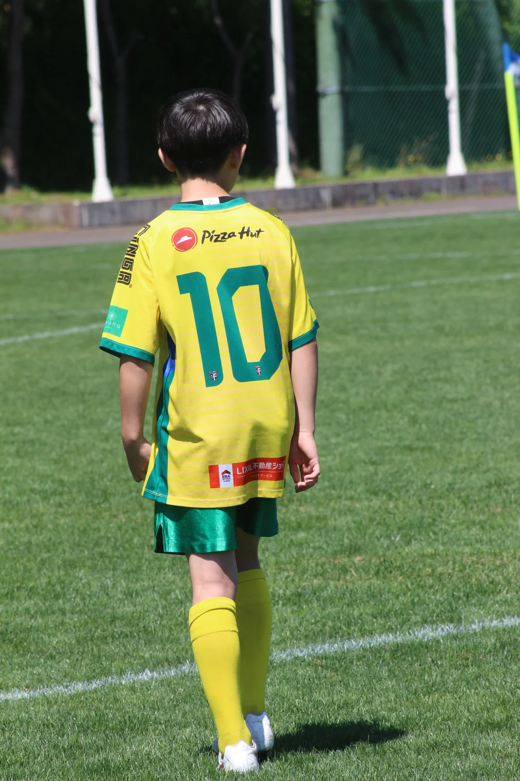 黄色の背番号10のユニフォームでピッチに立つ真栄FCの選手