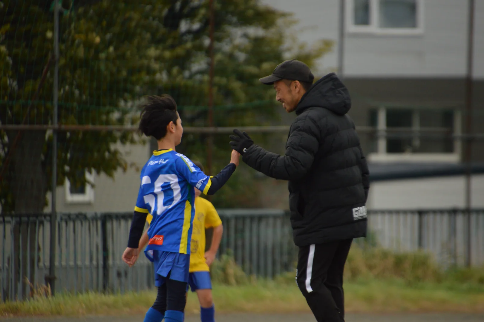 グラウンドで選手と手を合わせるしおコーチ